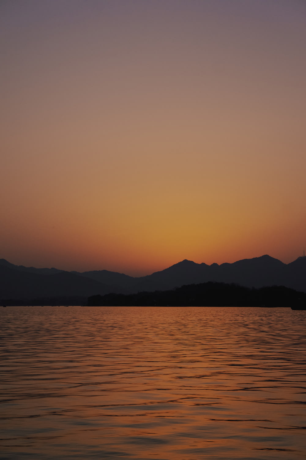 silhouette of mountain near calm sea during sunset