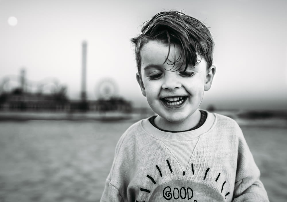 grayscale photo of smiling boy in sweater