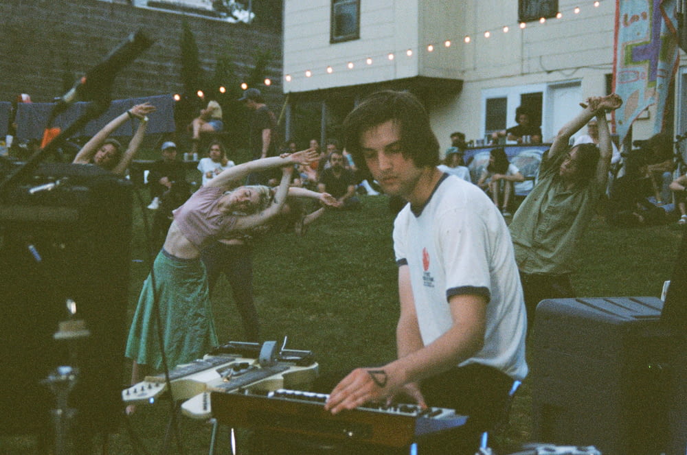 man playing electronic keyboard in front of people stretching and sitting