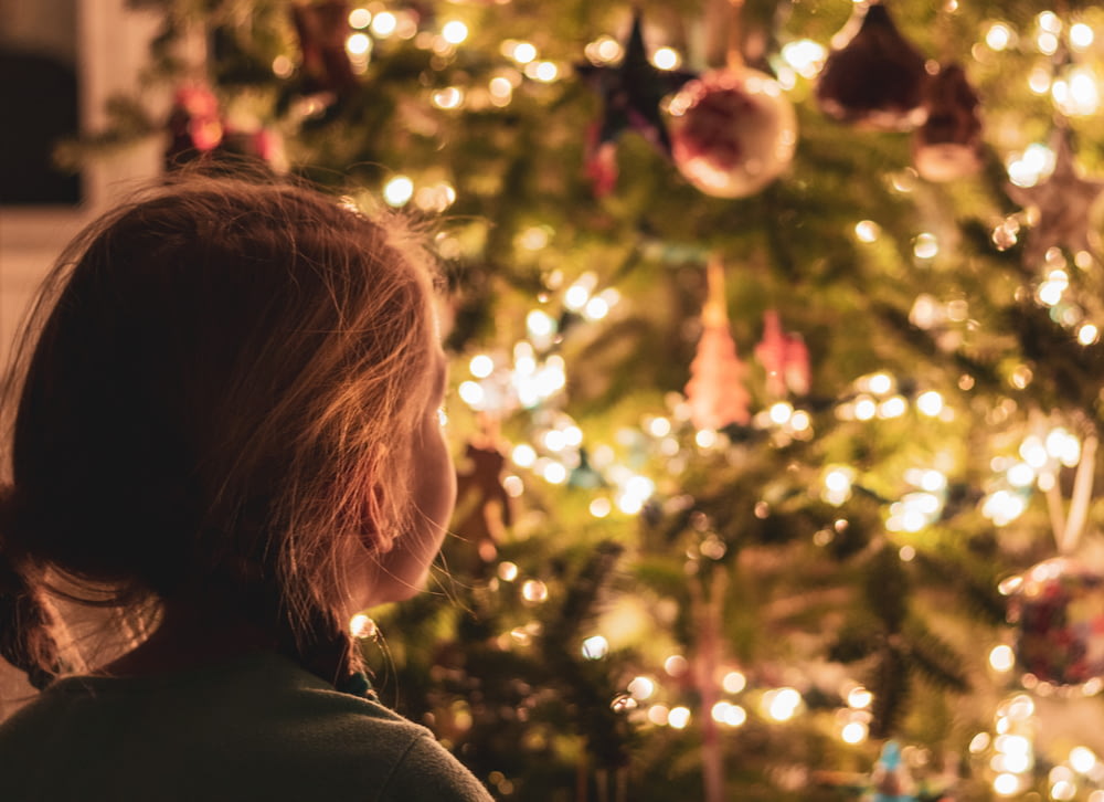 girl standing beside Christmas tree