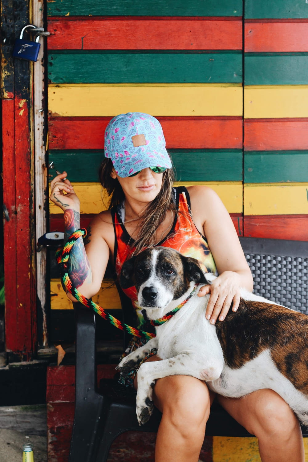 woman wearing blue baseball cap and orange tank top sitting on chair with dog