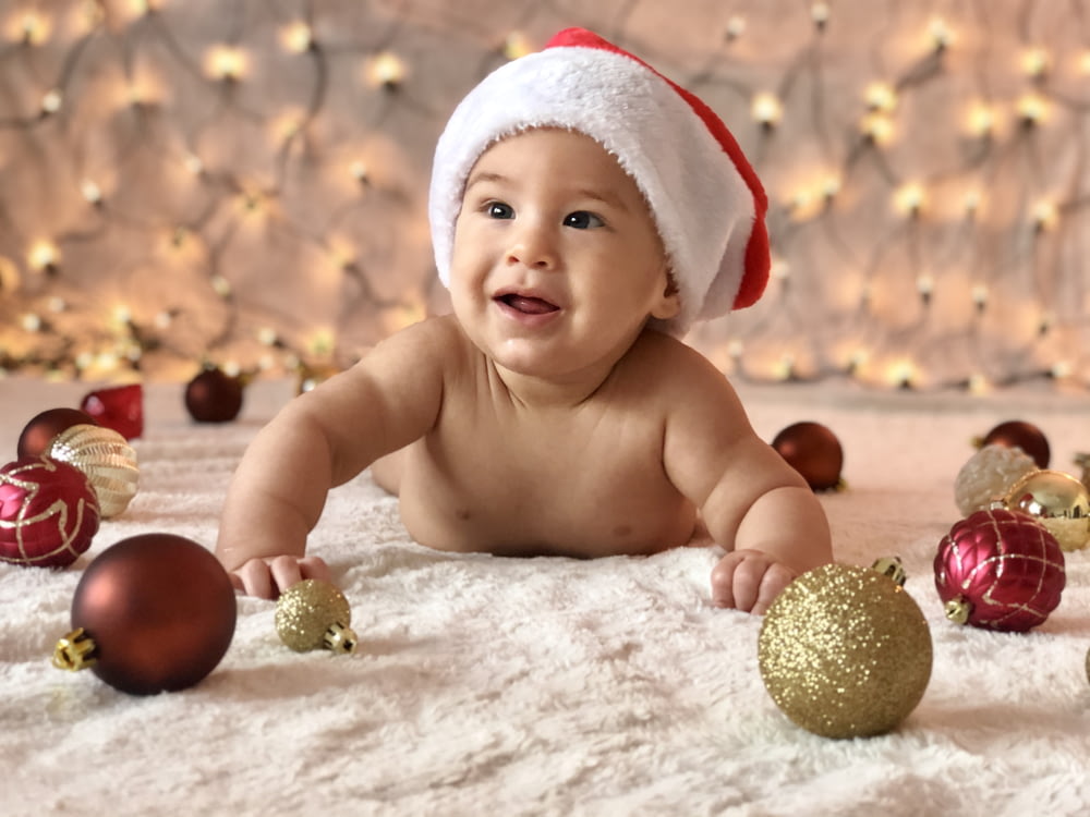 photographie en gros plan d’un bébé nu entouré de boules de Noël