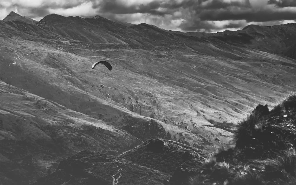 grayscale photo of person surfing on mountain