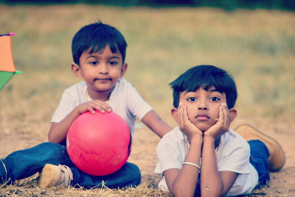twin children wearing white crew-neck t-shirt on brown field