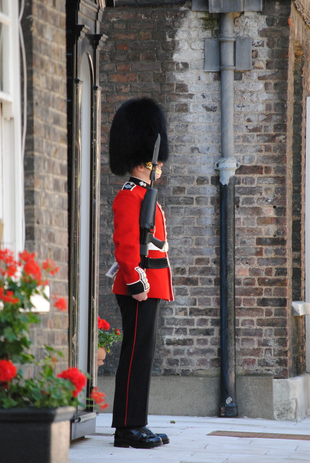 Person in roter und schwarzer Uniform, die tagsüber in der Nähe des schwarzen Metallpostens steht