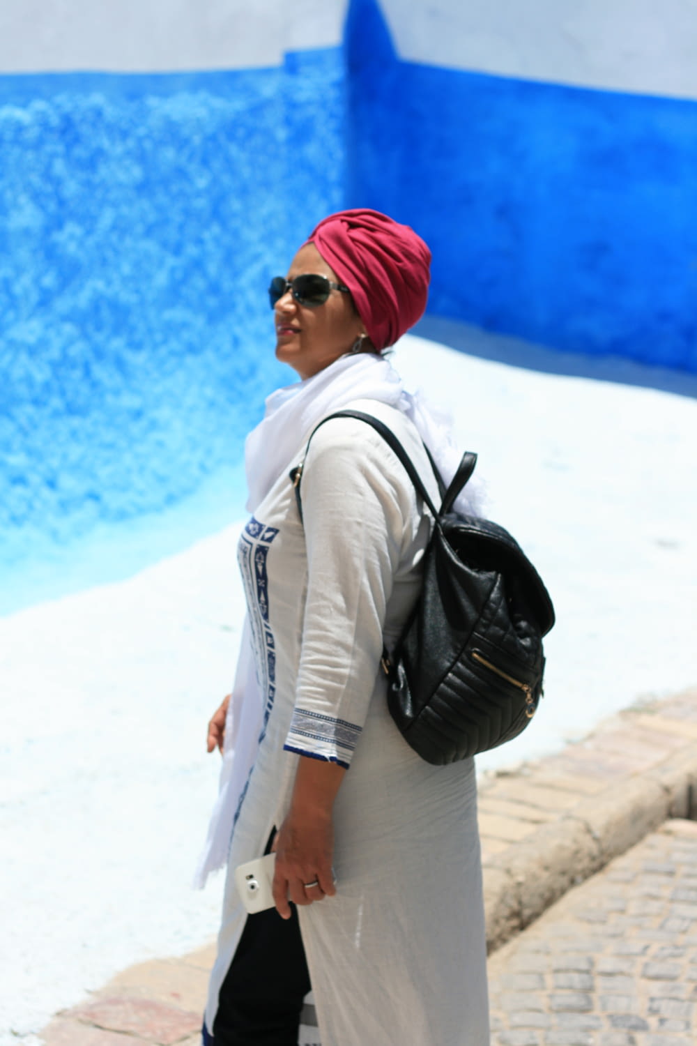 woman in white jacket and red knit cap standing on white sand during daytime
