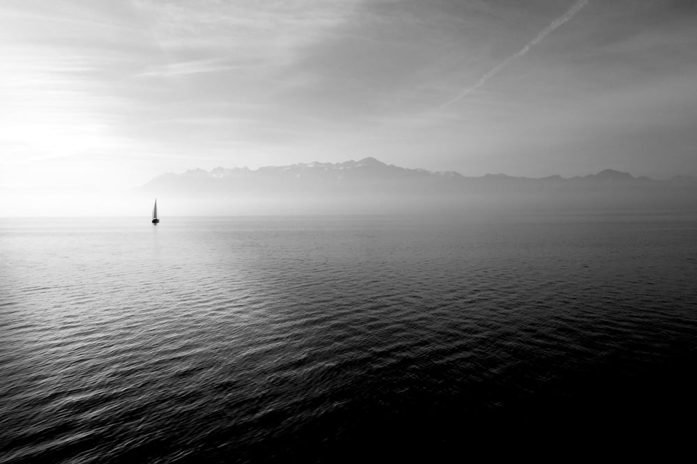 veleiro em corpo calmo de água sob o céu branco durante o dia