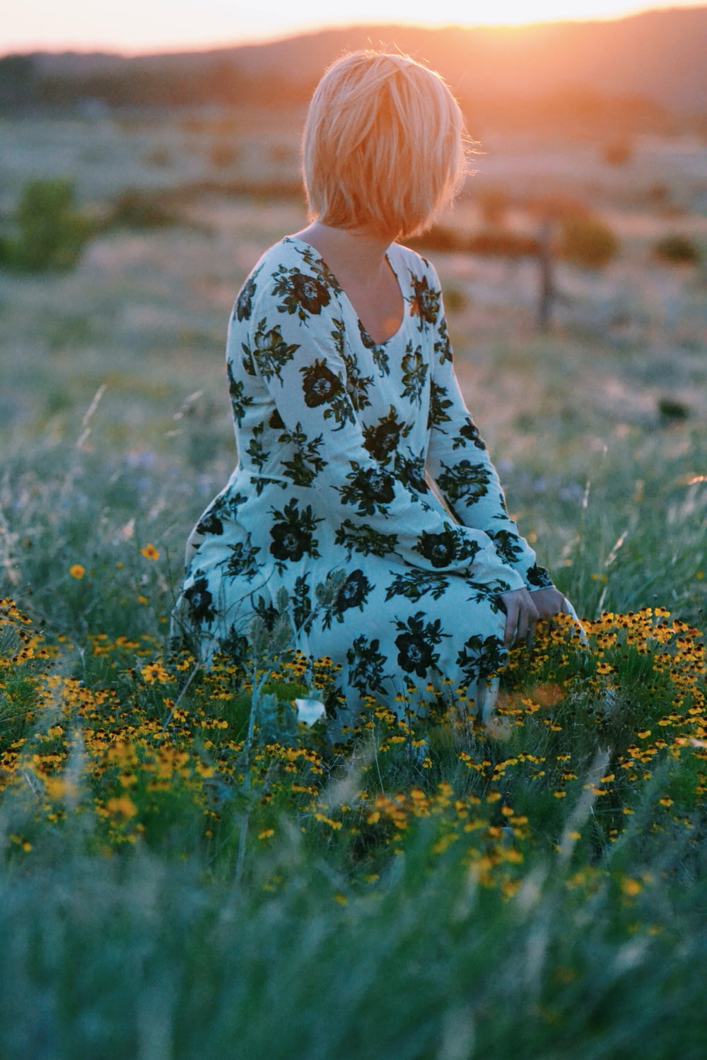 woman sitting on yellow flower field during daytime