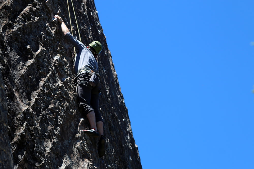 man performing wall climbing under clear sky