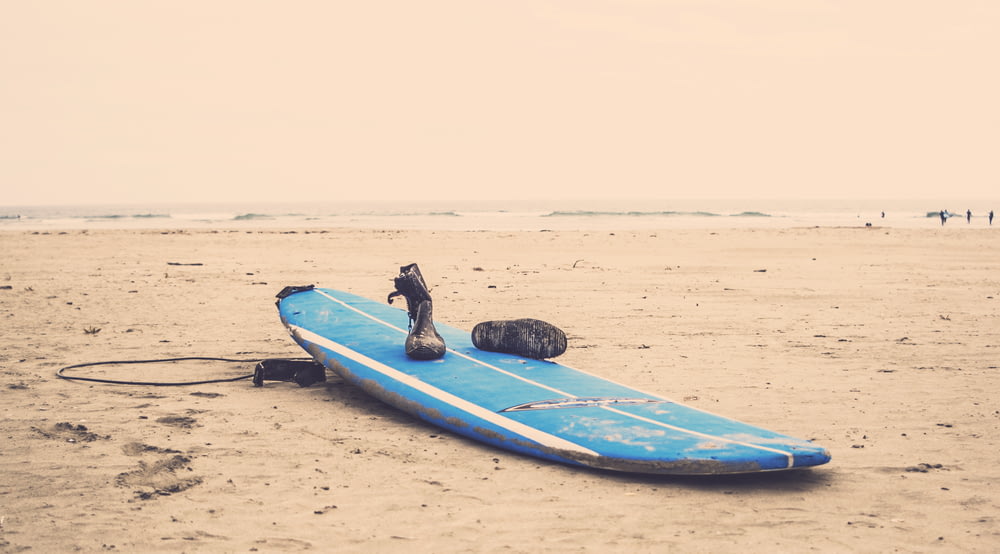 Tabla de surf azul sobre arena gris