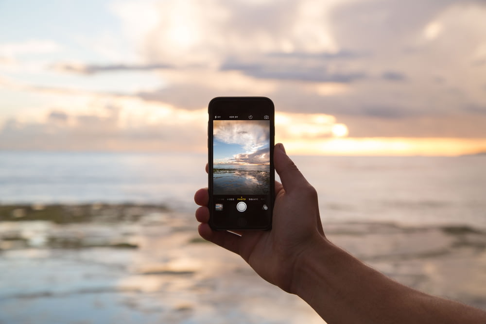 personne tenant un smartphone montrant l’océan