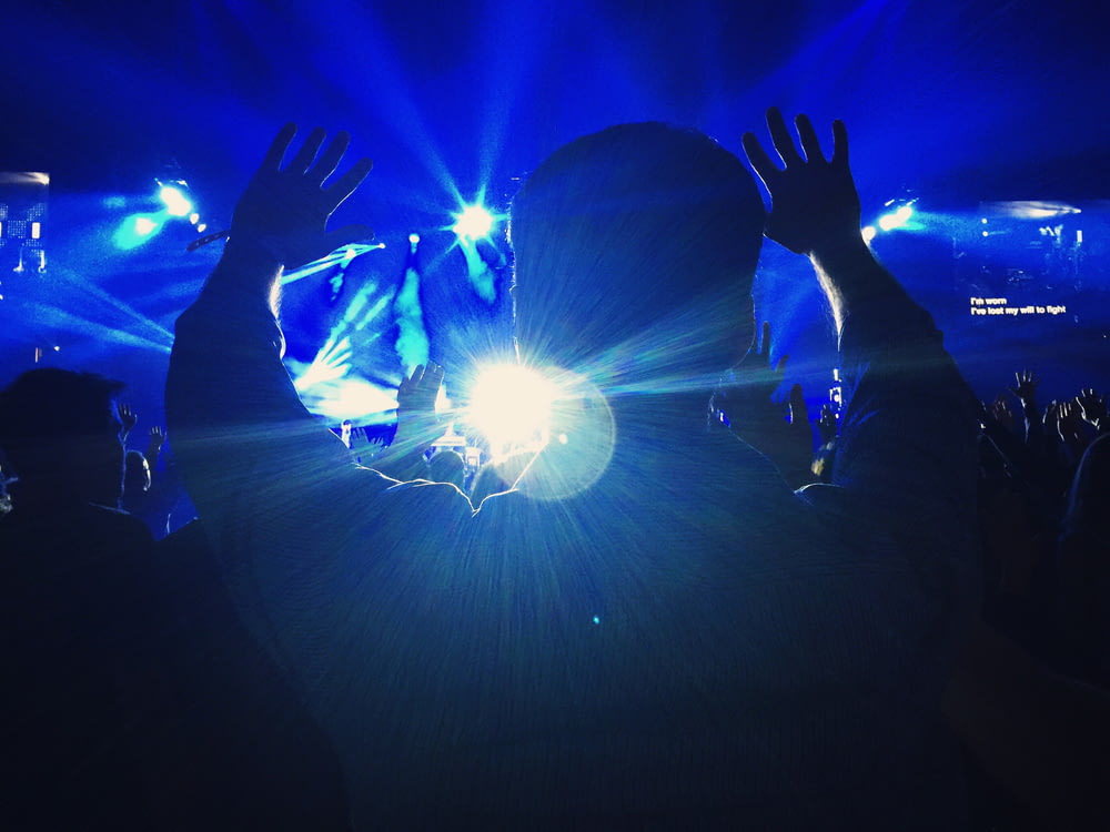 silhouette of a person raising hands towards the stage