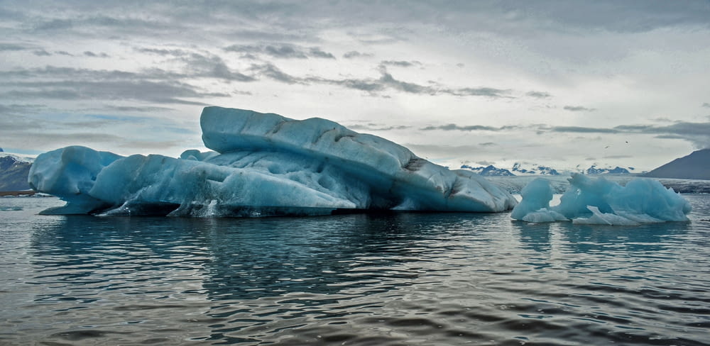 cuerpo de agua con iceberg bajo cielo nublado