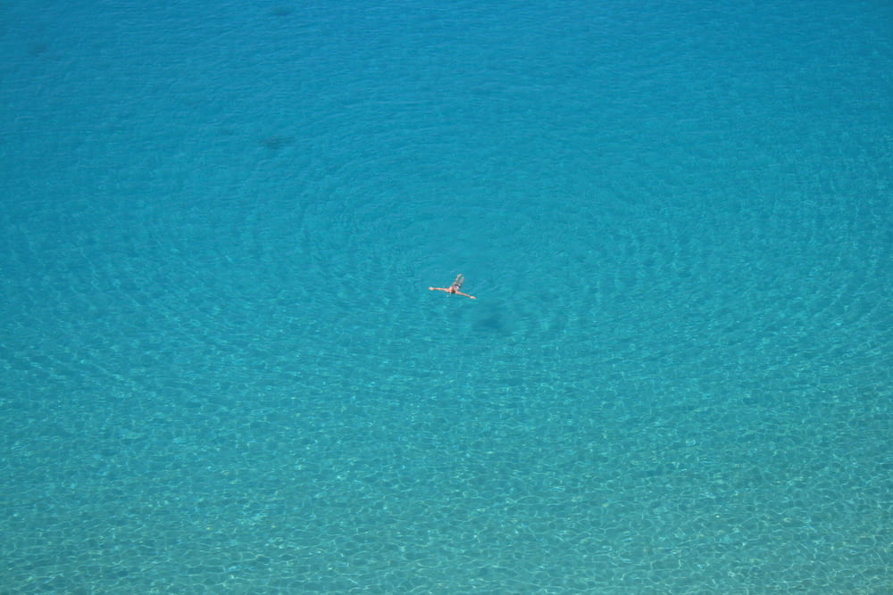 aerial photo of person swimming on body of water during daytime