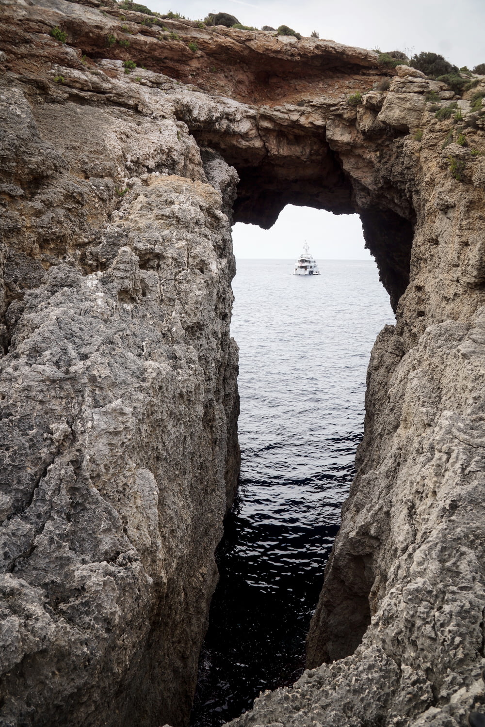 rock formation near sea with sailing ship