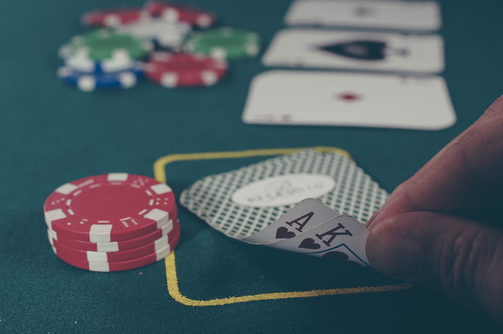 Person mit schwarzem Ass und Pik-König spielt Karten am Pokertisch