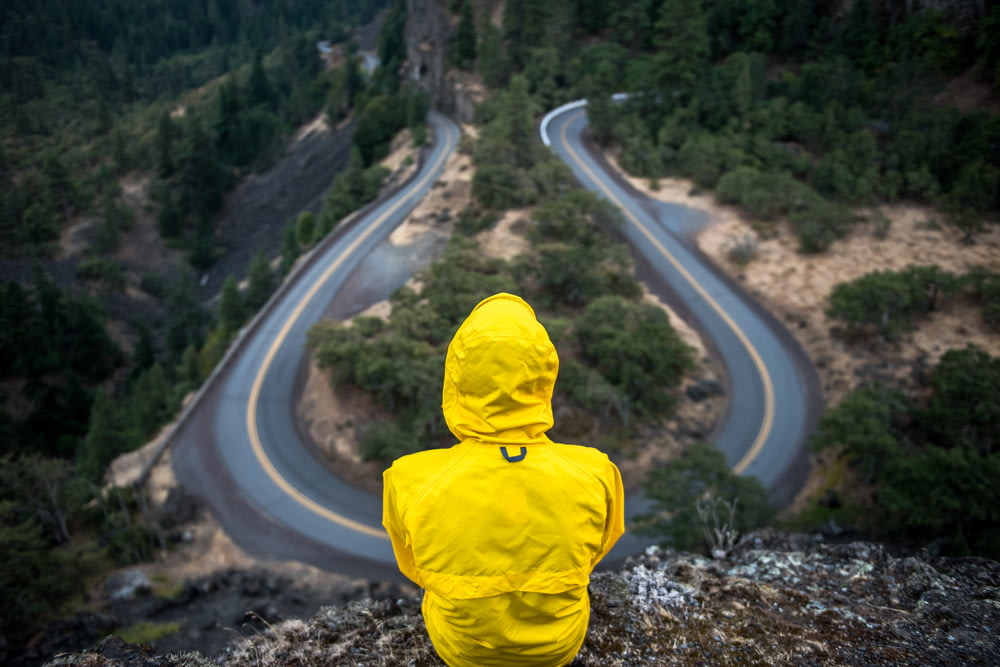 Persona con abrigo amarillo de pie en la cima de la colina