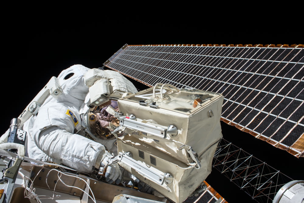 Nahaufnahme eines Astronauten, der einen Satelliten repariert