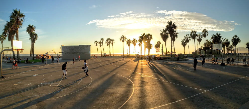 people playing basketball at court during sunset