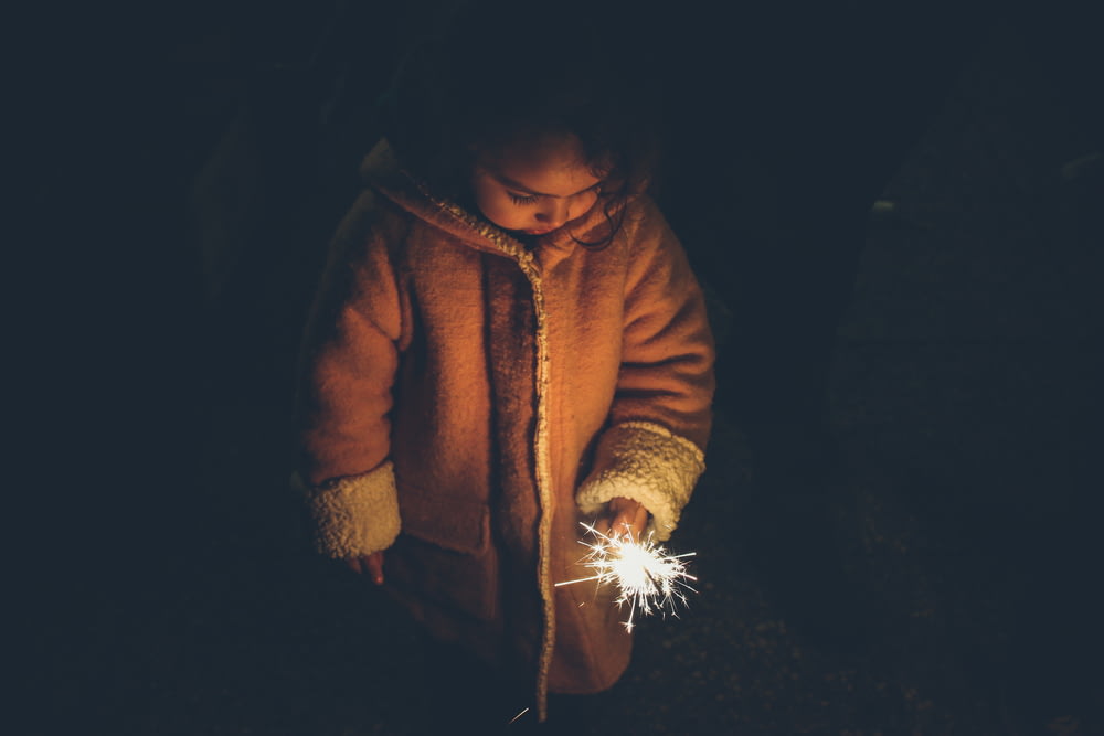 girl holding sparkler at nighttime
