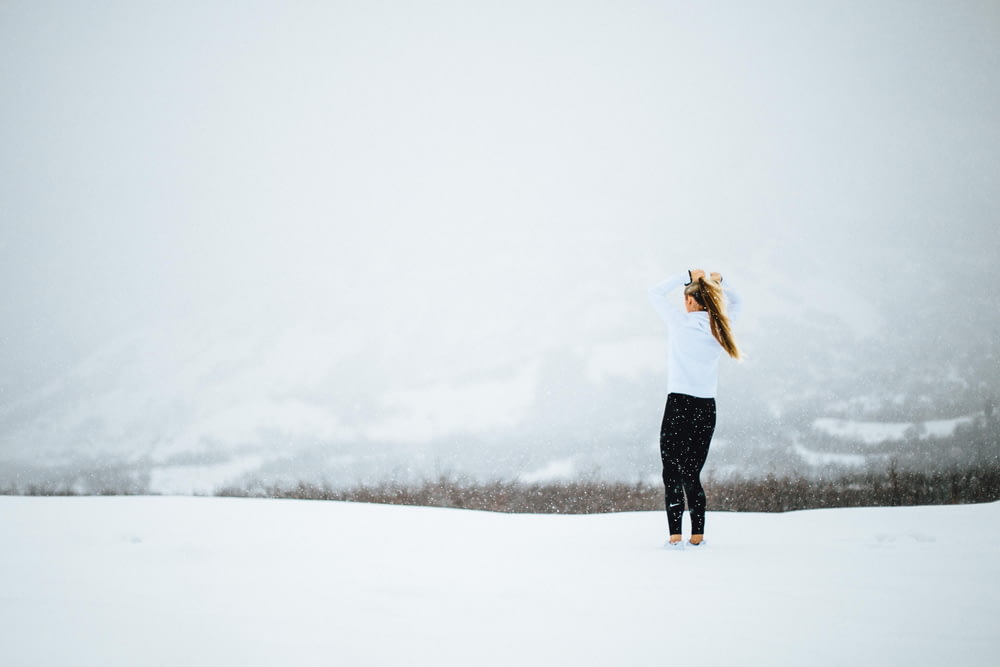 woman standing on open field covered in snow at daytime