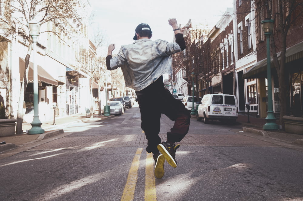 homem pulando no meio da rua durante o dia