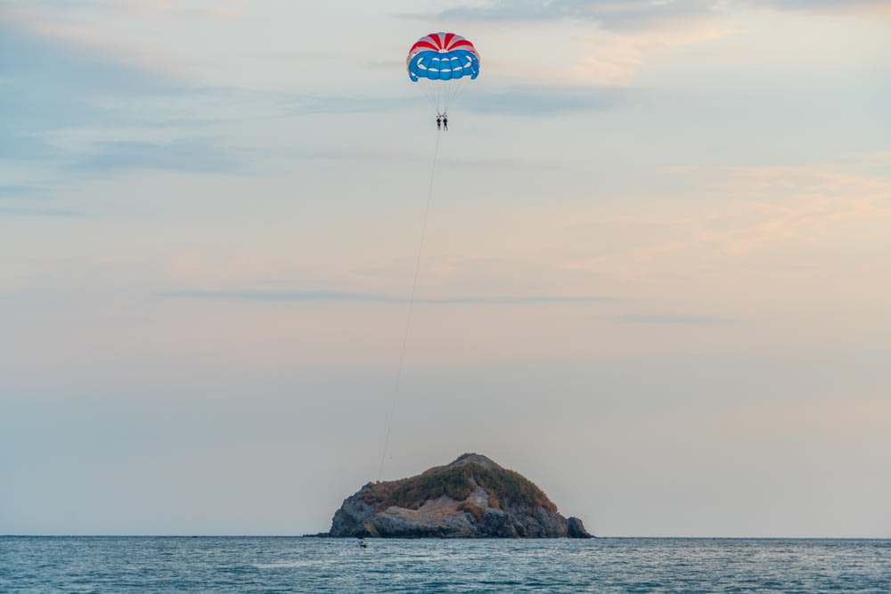two people paragliding towards islet