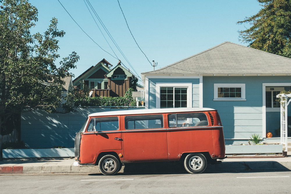 red Volkswagen Samba parked in front of teal house