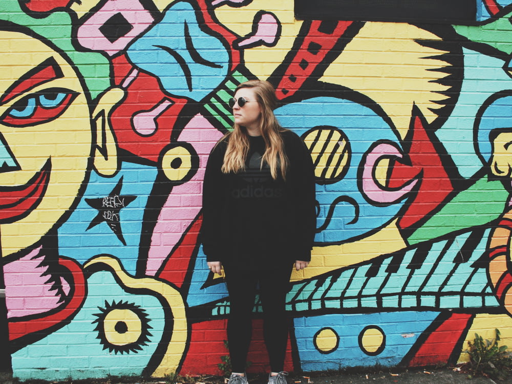 femme debout à côté du mur avec des graffitis
