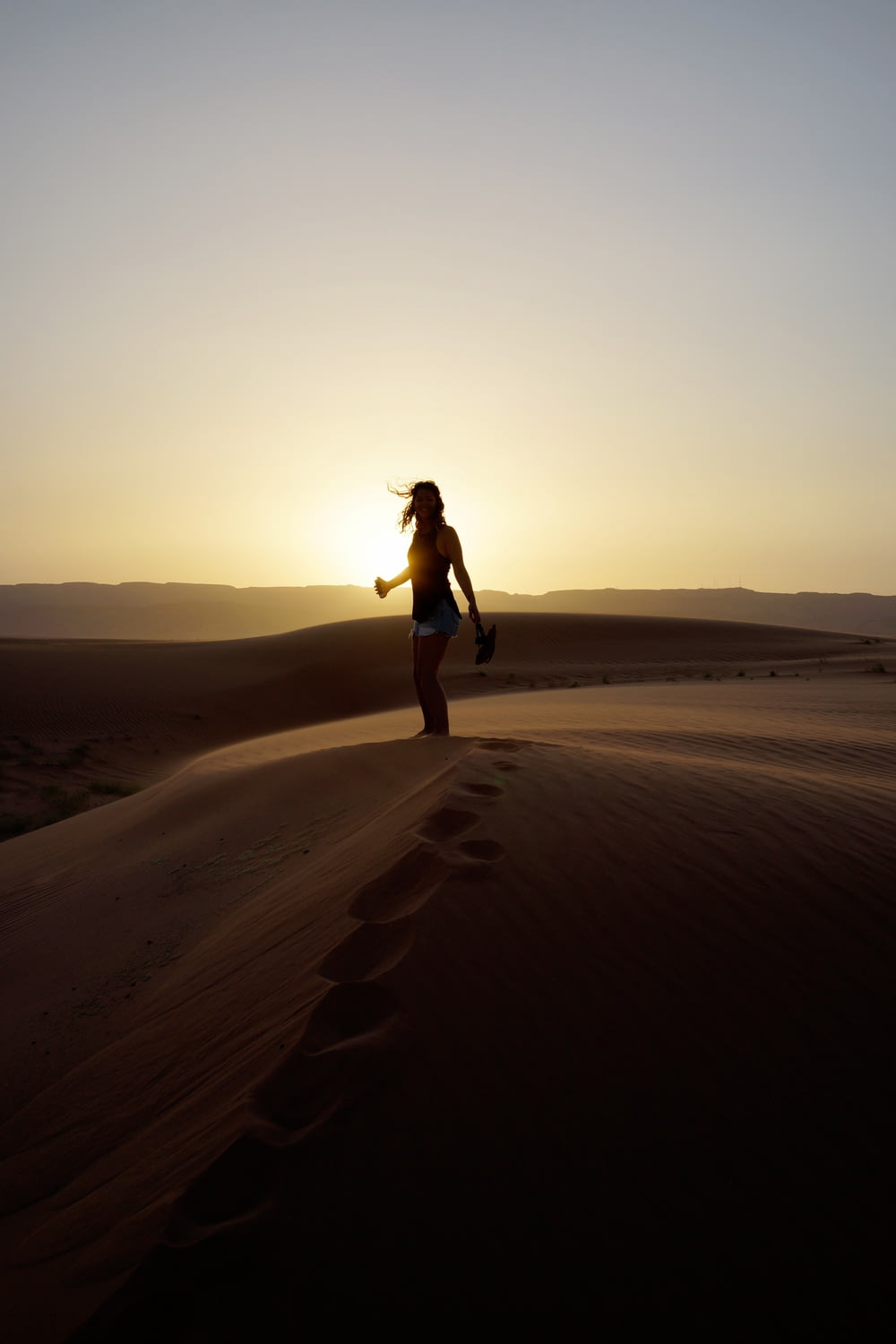 woman standing on sand during sunset