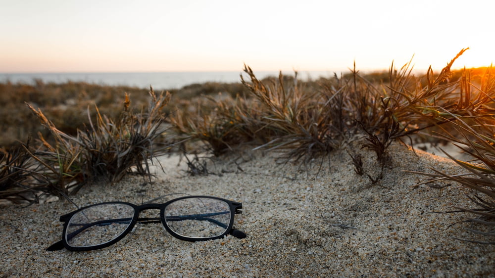 clear eyeglasses with black frames on sand