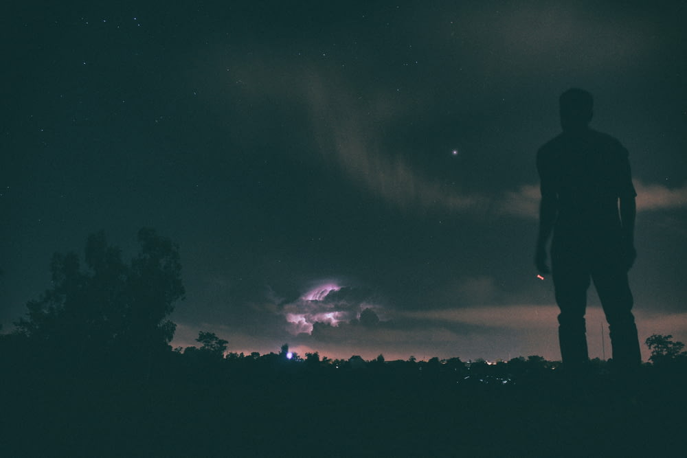 silhouette of man standing under night sky