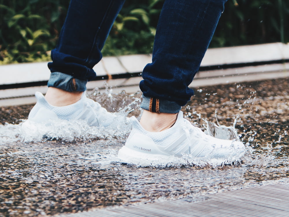 person wearing pair of gray adidas UltraBOOST low-top sneakers stepped on pool of water