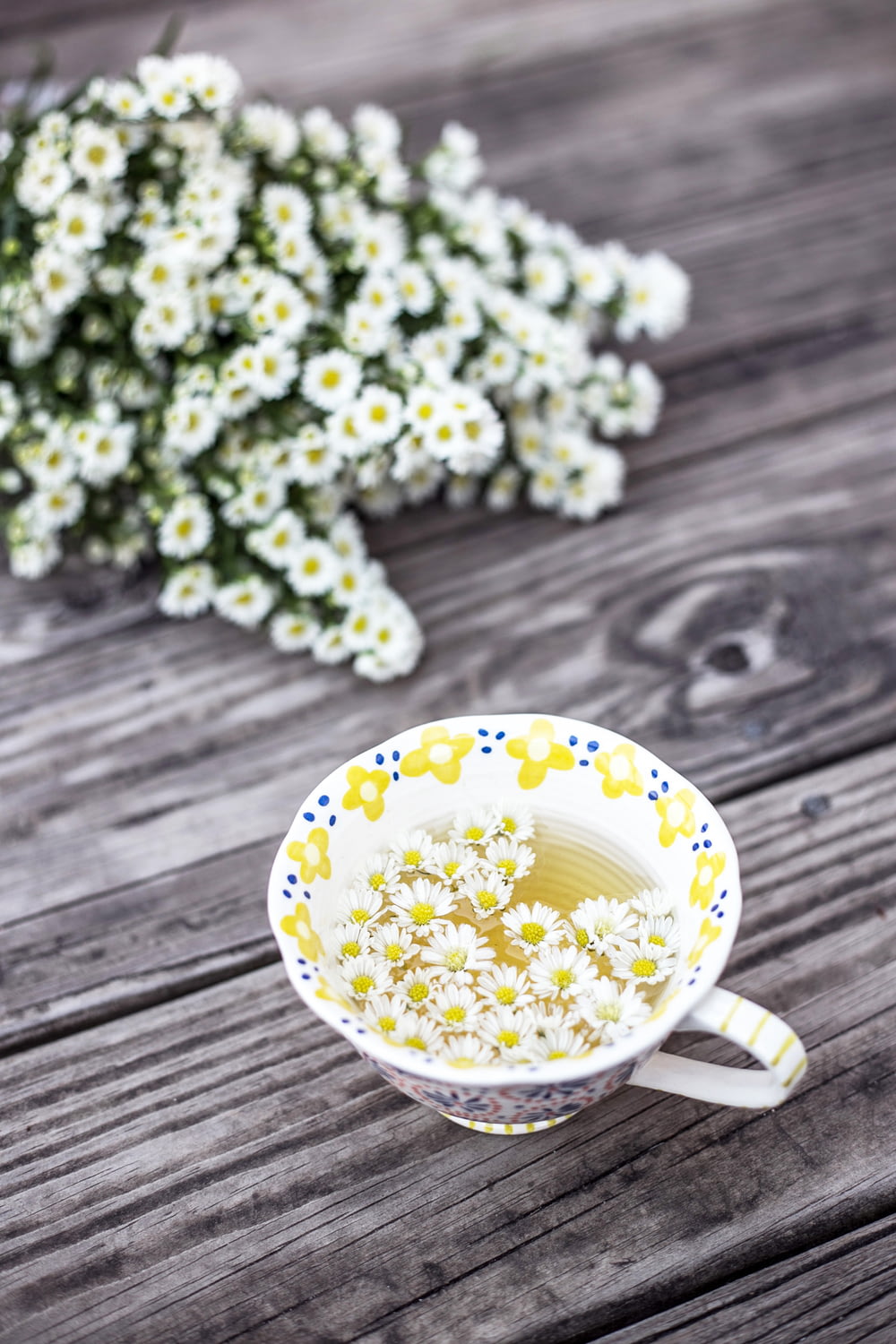 copo branco e amarelo com flores na mesa
