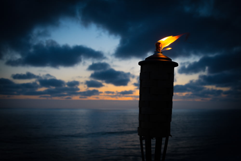 lighted tiki torch near sea at night