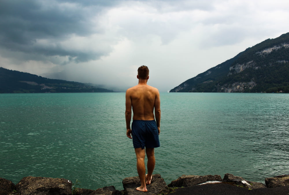Mann in schwarzen Shorts steht vor Gewässer