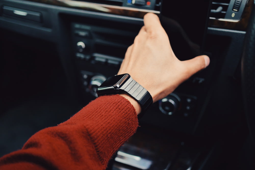 Fotografia di messa a fuoco selettiva della persona con l'orologio intelligente che guida l'auto