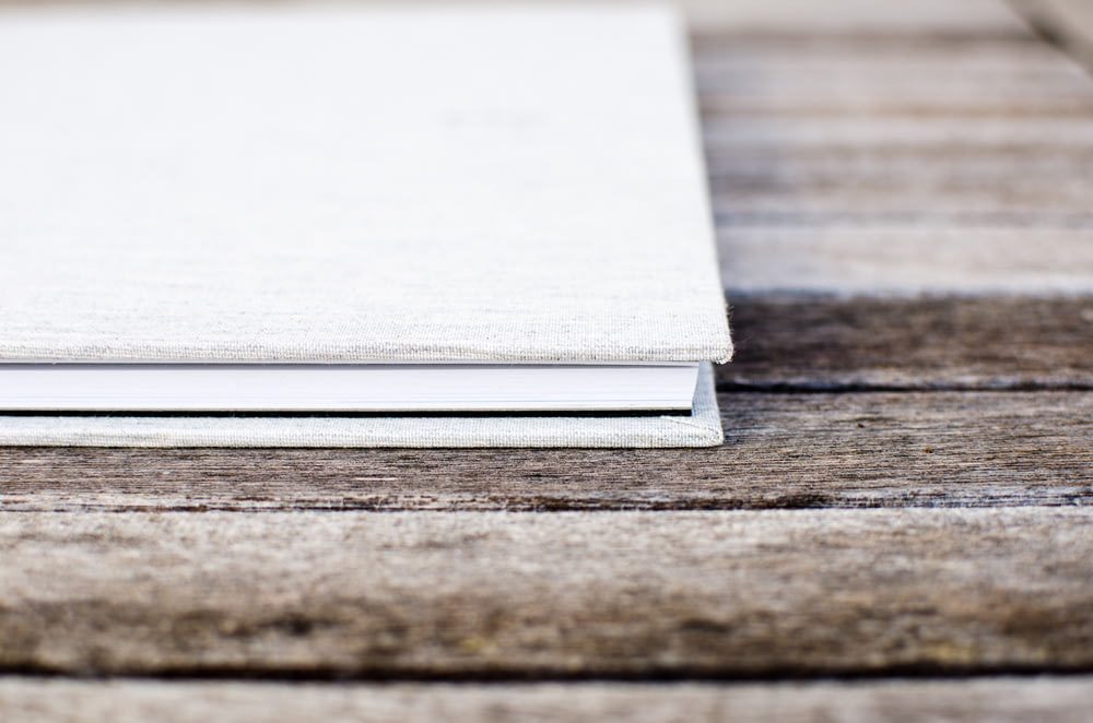 Livro branco de capa dura sentado na mesa de madeira
