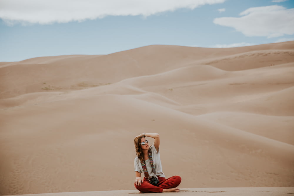fotografia minimalista da mulher sentada no chão do deserto