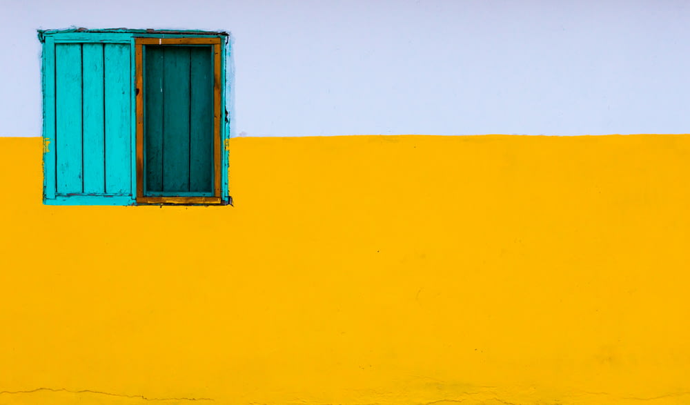 gelb und weiß gestrichene Wand mit blauem Fenster