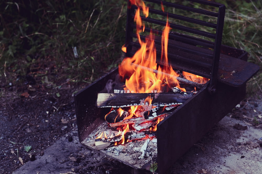 brown metal grill with firing firewood