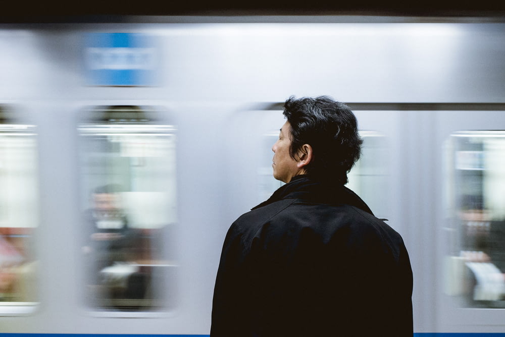 Fotografía de primer plano del hombre de pie delante del tren