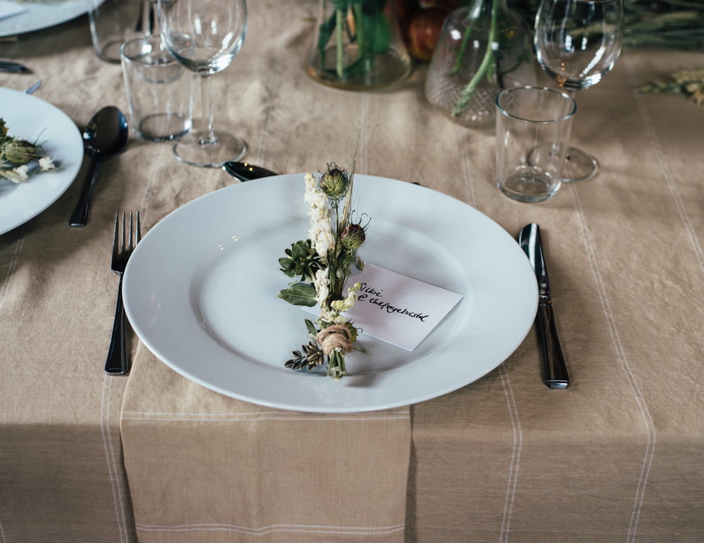 fleur décorative verte et blanche sur assiette blanche et couverts sur la table