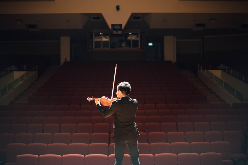 uomo in piedi davanti al palco che suona il violino