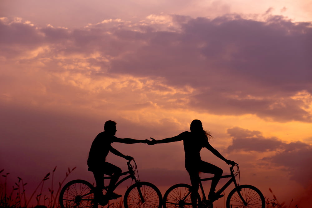 자전거를 탄 여자가 남자의 손을 잡으려고 손을 뻗는 모습 뒤에도 자전거를 타고