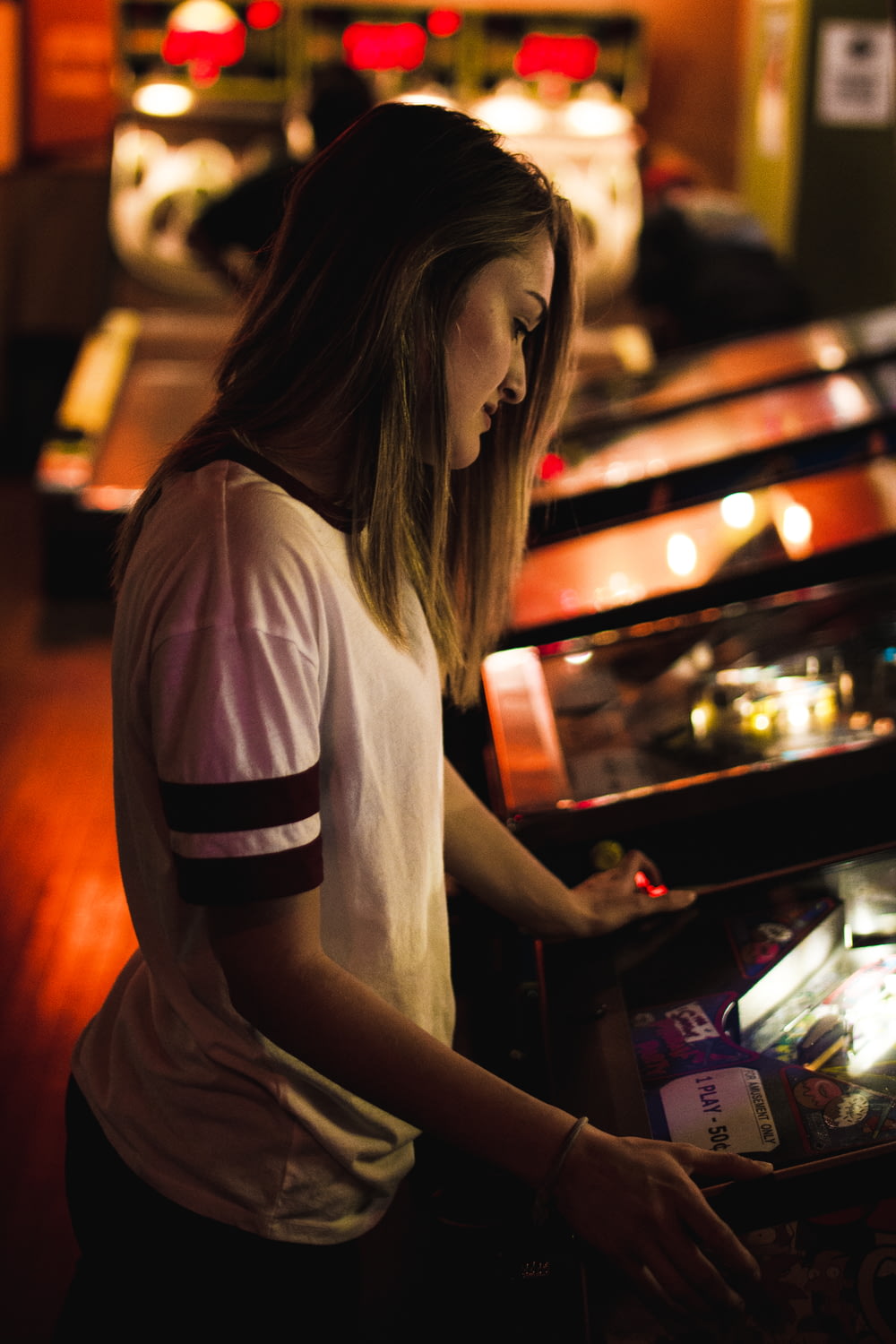 woman in white and black shirt standing in front of arcade machine