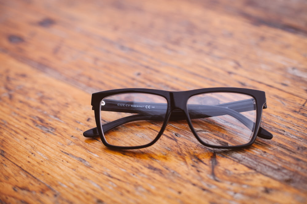 lunettes de style Wayfarer à monture noire sur une surface en bois