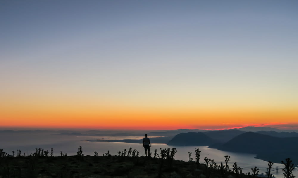 Foto de la silueta del hombre de pie en la montaña