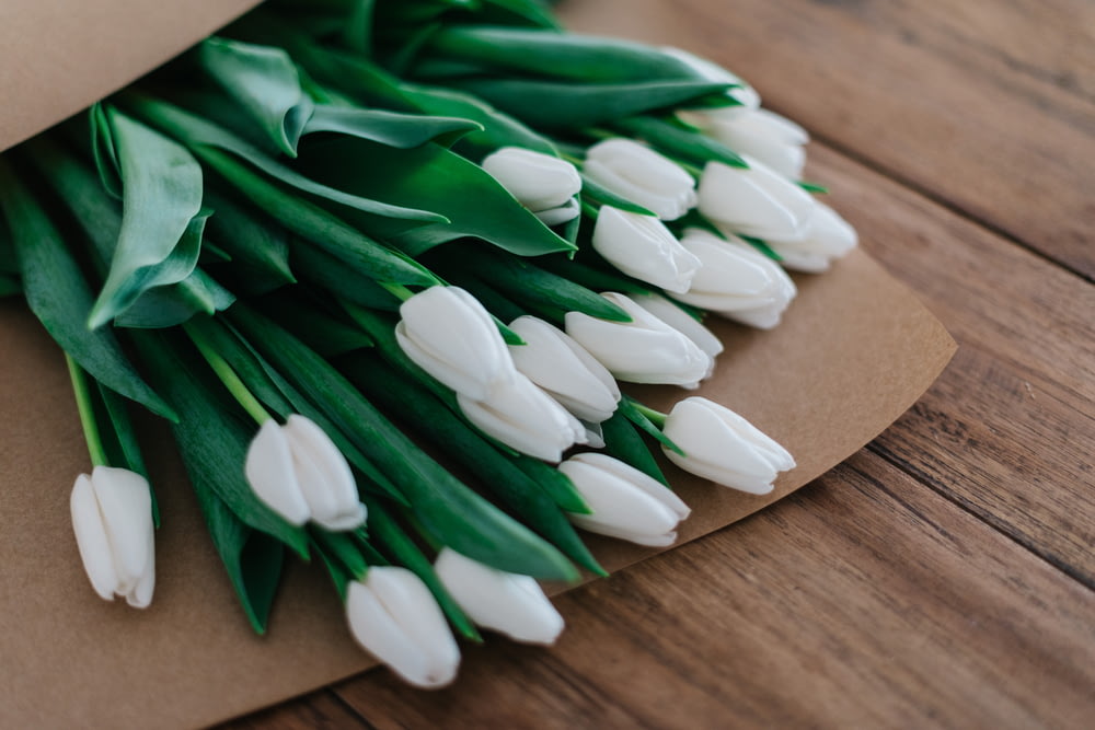 fotografia ravvicinata di bouquet di fiori dai petali bianchi su un tavolo di legno marrone