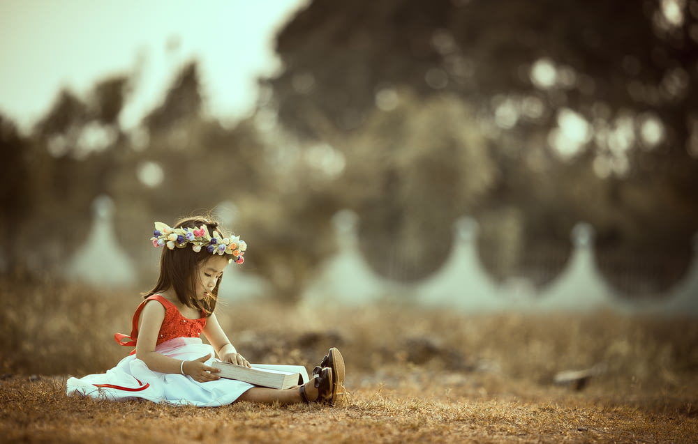 fille assise tenant un livre sur le terrain